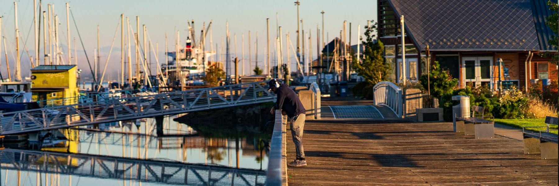 Person on pier near boats at sunset